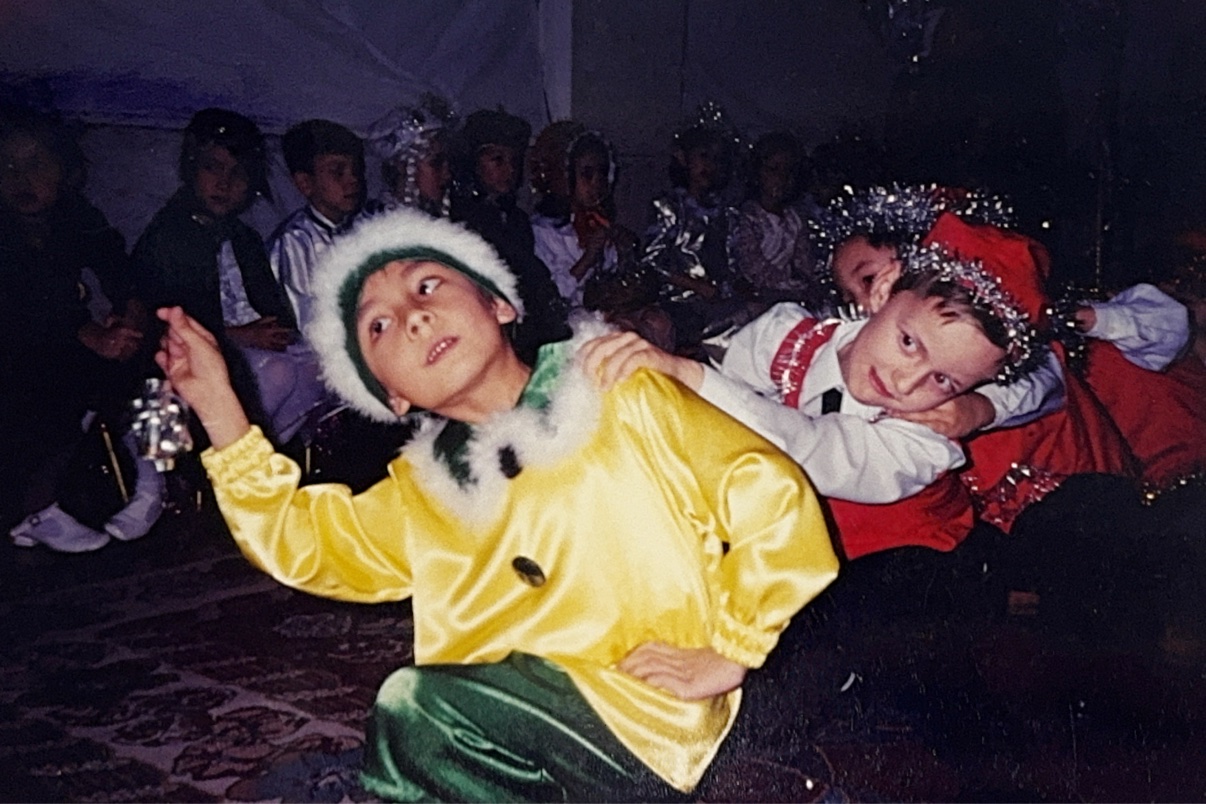 Young Eldor in a yellow top and green trousers, leading the gnomes at a kindergarten New Year’s Eve party