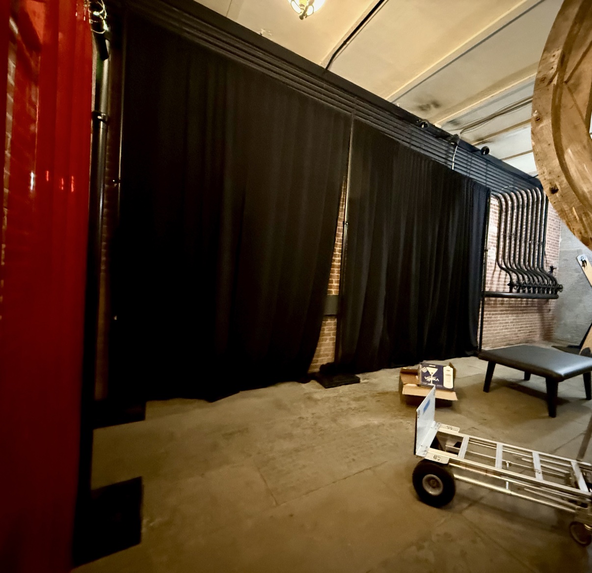 Black pipe and drape going up during the dark room build, red framing at the left and a dolly in the foreground