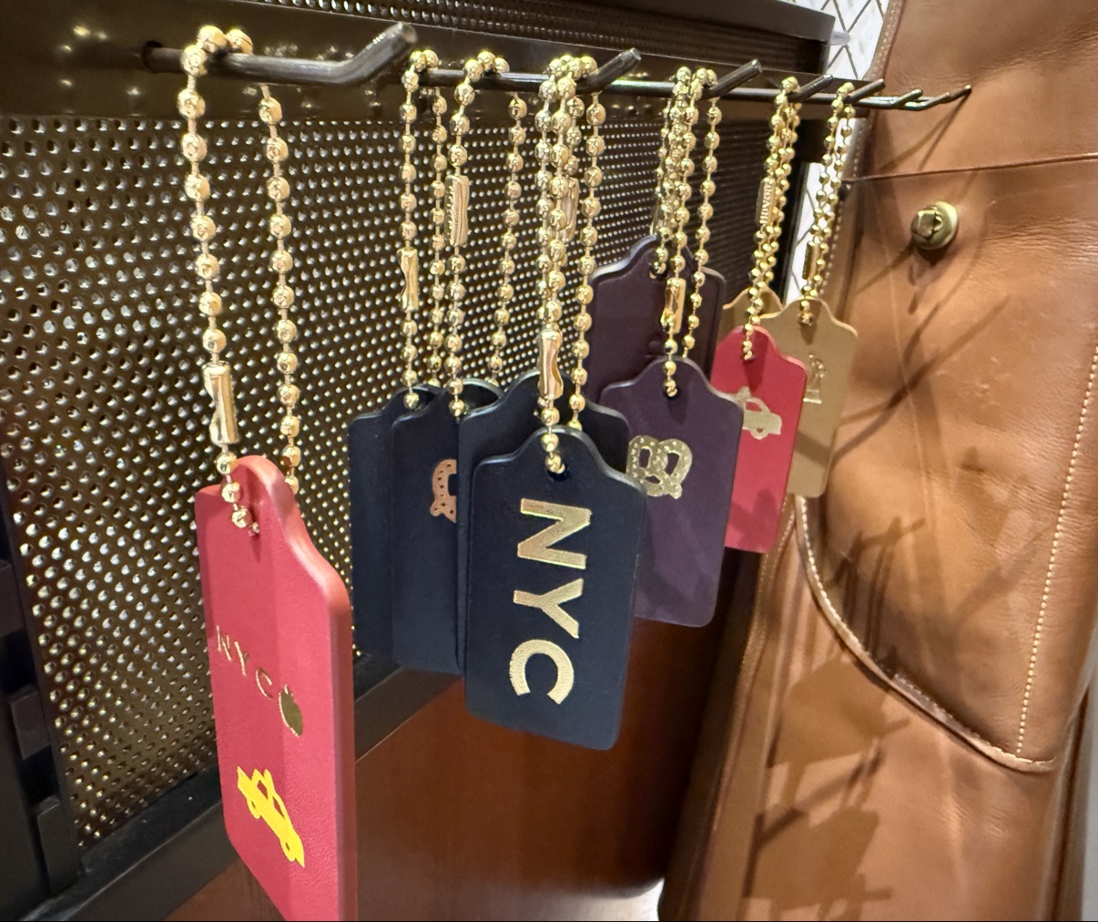 NYC-themed customized hangtags hanging on a rack — NYC letters, a pretzel stamp, a taxi and an apple