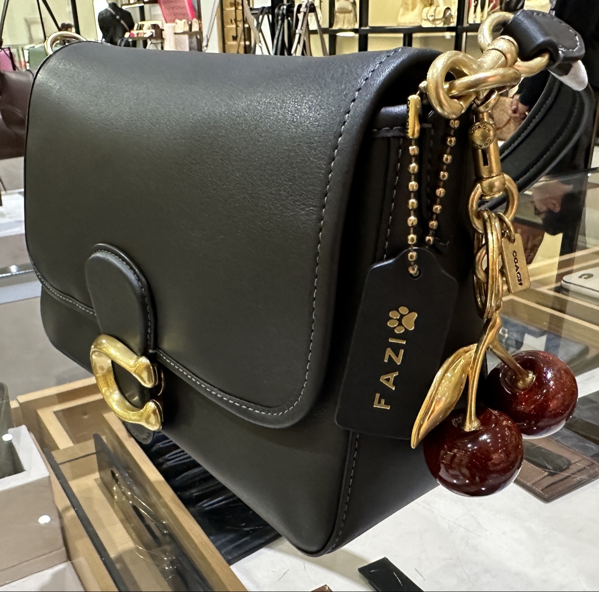 Black Coach bag with a customized black hangtag stamped FAZI with a paw print, and a glossy cherry charm