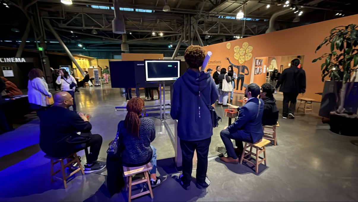 The store team spread out across a museum exhibition hall, with exhibits and a cinema area behind them
