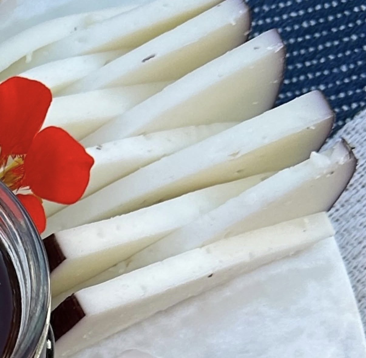 Close-up of sliced cheese with a red flower, from the charcuterie board